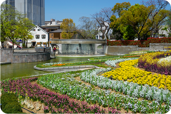色とりどりの花壇が広がる住吉公園と背後に見えるビル